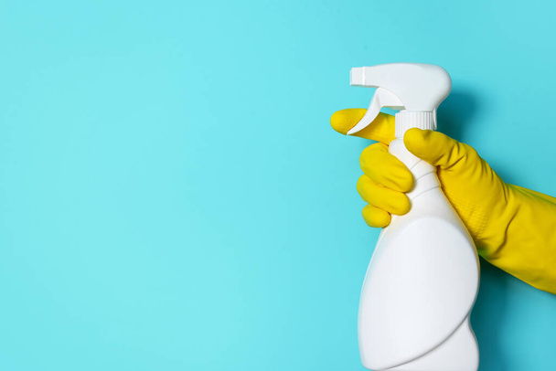 Hand in glove holding white plastic bottle of cleaning product, household chemicals. Copy space. Cleaning service concept. Household chemical cleaning products, brushes and supplies. Detergent bottle - Fotografie, Obrázek