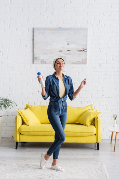 Lächelnde Hausfrau hält Lufterfrischer im Wohnzimmer  - Foto, Bild