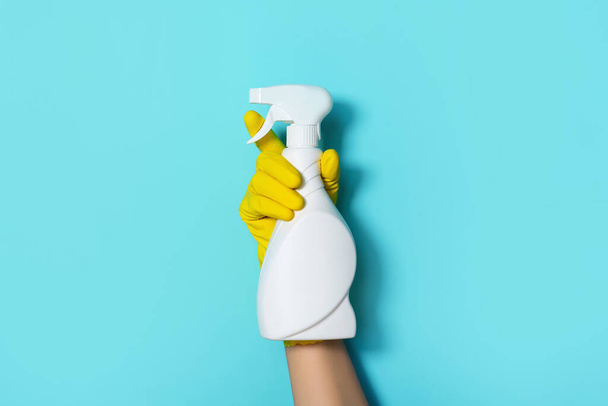 Hand in glove holding white plastic bottle of cleaning product, household chemicals. Copy space. Cleaning service concept. Household chemical cleaning products, brushes and supplies. Detergent bottle - Foto, Imagen