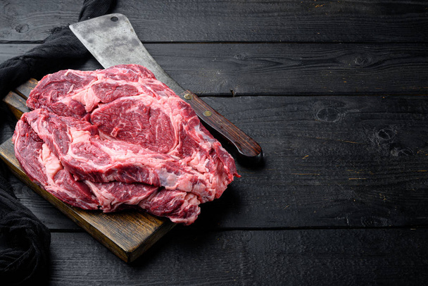 Ensemble de steak de côtelette de viande cru bio de premier choix, sur fond de table en bois noir, avec espace de copie pour le texte - Photo, image