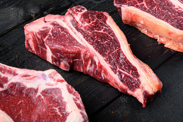 Vieilli à sec T-bone cru ou porterhouse viande de bœuf Ensemble de steak, sur fond de table en bois noir - Photo, image