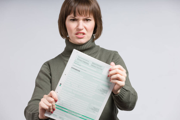 woman holding an empty tax form and makes a wry face - Photo, Image