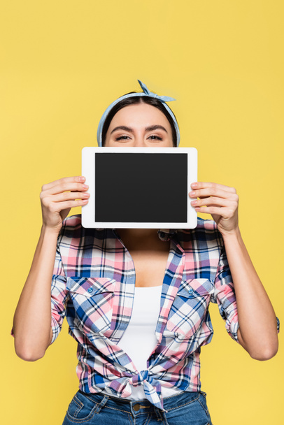 Housewife holding digital tablet near face isolated on yellow  - Фото, изображение