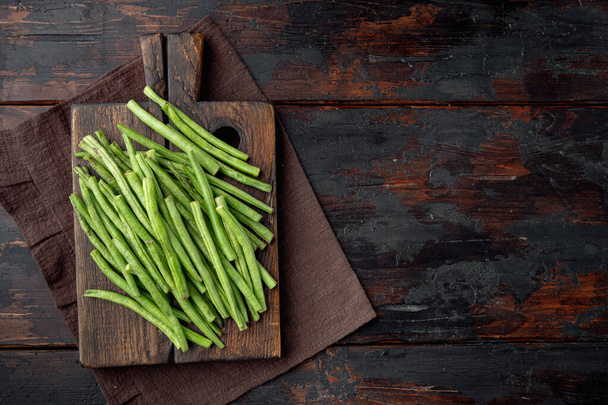 Fresh green French beans set, on wooden cutting board, on old dark  wooden table background, top view flat lay, with copy space for text - Foto, immagini