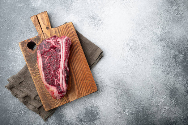 Klubový syrový steak s bylinkami a solí připravený na vaření, na šedém kamenném pozadí, horní pohled plochý ležel, s kopírovacím prostorem pro text - Fotografie, Obrázek