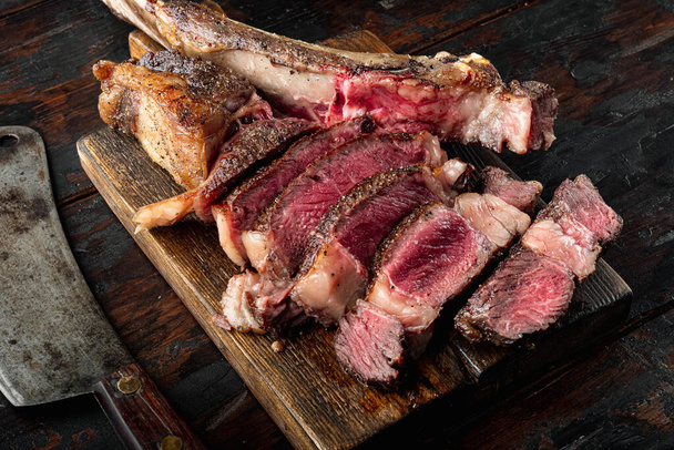 Közepes ritka marhahús steak készlet, tomahawk vágott, fa tálalóasztalon, régi sötét fa asztal háttér - Fotó, kép