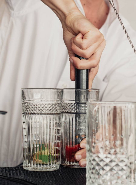 Barman bereidt mojito 's voor met gerijpte rum, munt en natuurlijk fruit - Foto, afbeelding