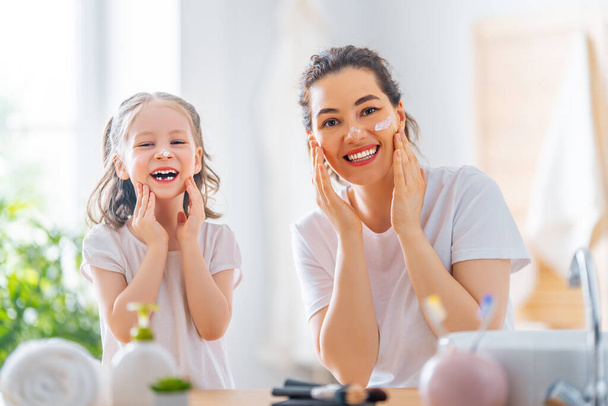 Happy family! Mother and daughter child girl are caring for skin in the bathroom. - Φωτογραφία, εικόνα