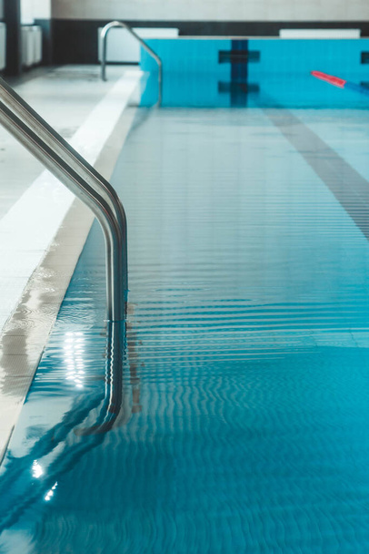 a water pool with blue transparent clear water, on which bright sunlight shines. Water lanes in the swimming pool. indoor sports field for swimming. - Фото, изображение