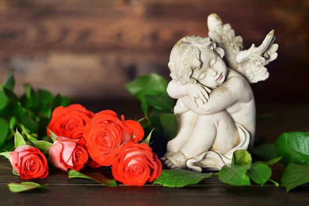 Άγγελος φύλακας και τριαντάφυλλα σε ξύλινο φόντο  - Φωτογραφία, εικόνα