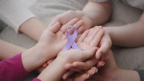 Symbol povědomí o domácím násilí. Zblízka záběr rodičů a dětí ruce drží fialovou stuhu - Záběry, video