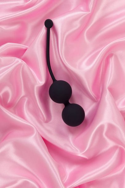 Μπάλες Αφροδίτης σε ροζ σατέν φόντο. Δάπεδο πυέλου και γυναικείο σεξουαλικό παιχνίδι. - Φωτογραφία, εικόνα