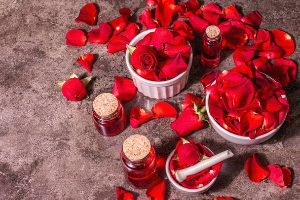 Agua de rosas con pétalos de rosa. Hacer esencia de rosa orgánica para cocinar Kerala India. Aromaterapia, relajación del spa, concepto de cosméticos. Luz dura moderna, sombra oscura. Fondo de piedra, vista superior - Foto, Imagen