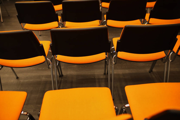 Černá a oranžová plastová konferenční křesla. černá a oranžová křesla v konferenční místnosti. pozadí černých a oranžových židlí. - Fotografie, Obrázek