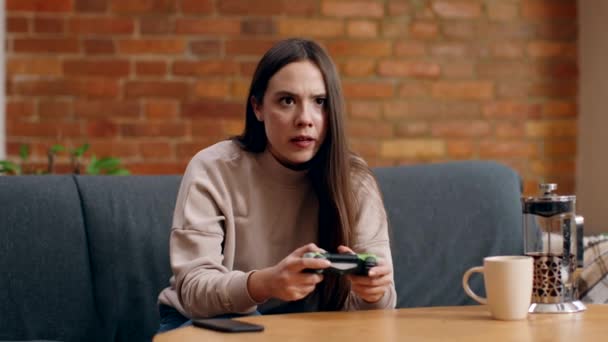 Giovane signora autoisolata che gioca ai videogiochi sul gamepad a casa, perde e si sente sconvolto, seduto sul divano - Filmati, video