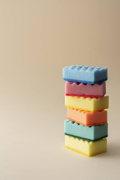 Pila de esponjas lavavajillas multicolores sobre fondo beige neutro, hogar de cocina y concepto de limpieza - Foto, imagen