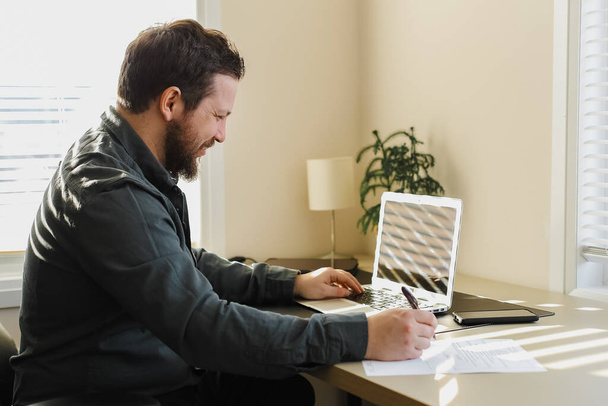 Homme d'affaires européen remplissant des documents et travaillant avec un ordinateur portable. - Photo, image