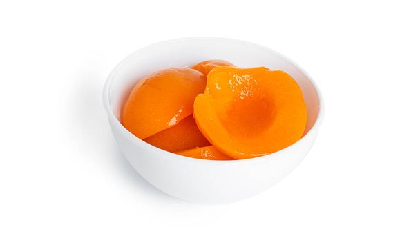 Консервированные персики в белой миске. Сладкие персики в сиропе изолированы на белом фоне. - Фото, изображение