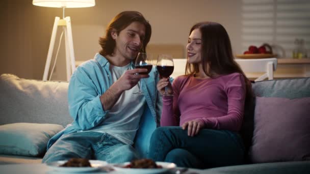 Молодая пара влюблена, пьет вино вместе, мужчина тост с подругой, проводит романтический вечер вместе дома - Кадры, видео