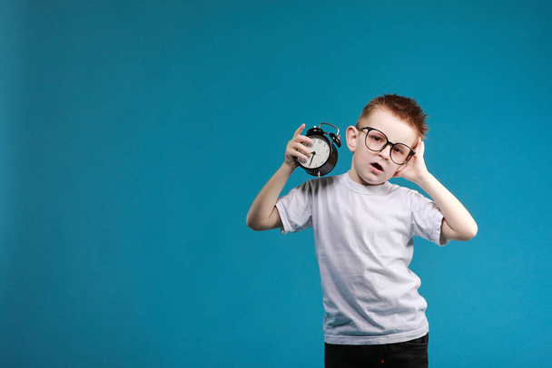 Little boy waking up with alarm clock, isolated on the blue background. Define your own rhythm of life. Happy hours concept. Schedule and timing. - Photo, Image