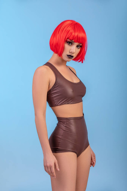 Portrait of beautiful sexy woman in red wig Bob hairstyle on blue background - 写真・画像