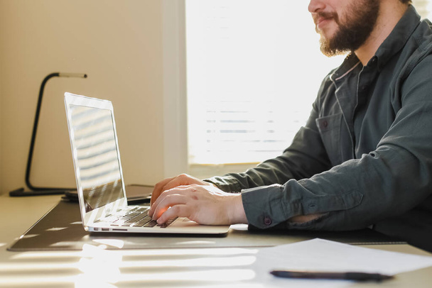 Blogueur masculin écrit article sur ordinateur portable au bureau. - Photo, image