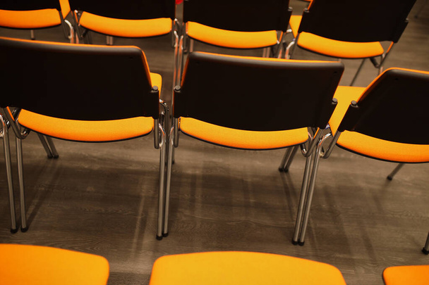 Zwarte en oranje plastic conferentiestoelen. zwarte en oranje stoelen in de vergaderzaal. achtergrond van zwarte en oranje stoelen. - Foto, afbeelding