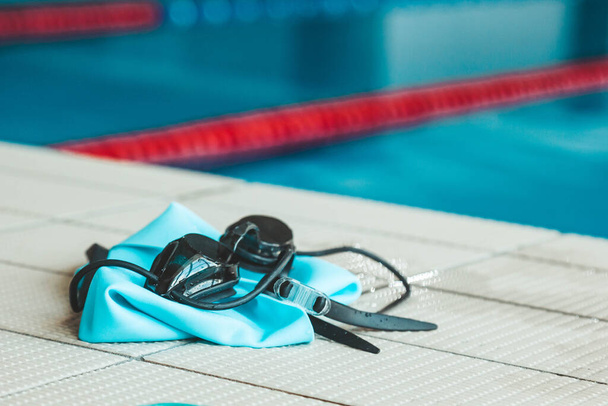 swimming goggles are on the parapet near the swimming pool. indoor swimming sports equipment. - Foto, afbeelding