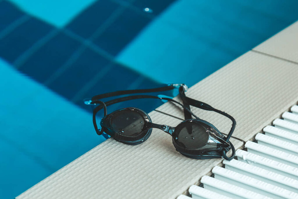 swimming goggles are on the parapet near the swimming pool. indoor swimming sports equipment. - Fotoğraf, Görsel