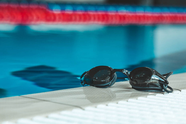 gafas de baño están en el parapeto cerca de la piscina. equipo deportivo de natación interior. - Foto, Imagen