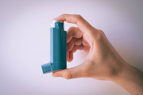 Human hand picking up an asthma inhaler - Foto, Imagen
