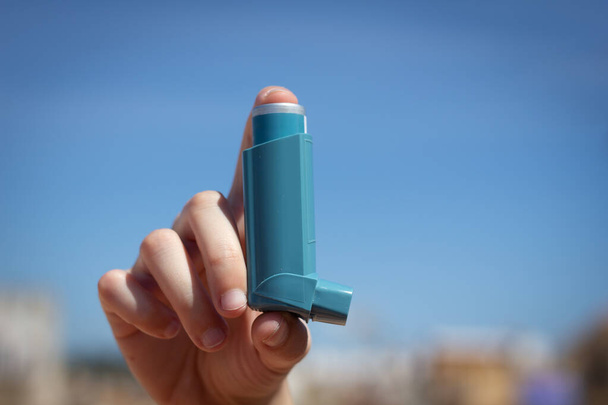 Menschliche Hand nimmt Asthma-Inhalator auf - Foto, Bild