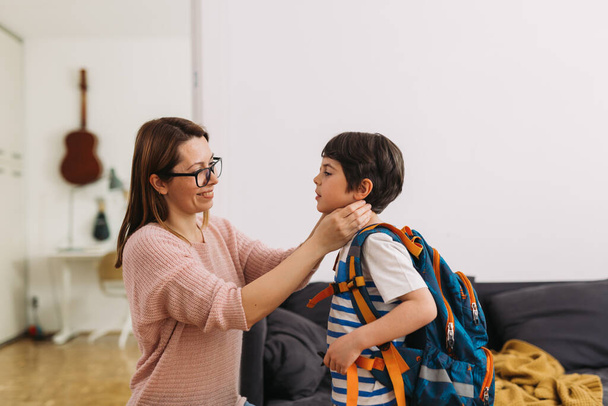 mother preparing her son for first day at school - Foto, Bild