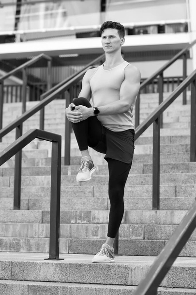 Muscular athlete warming up joints before morning jog - Foto, Bild
