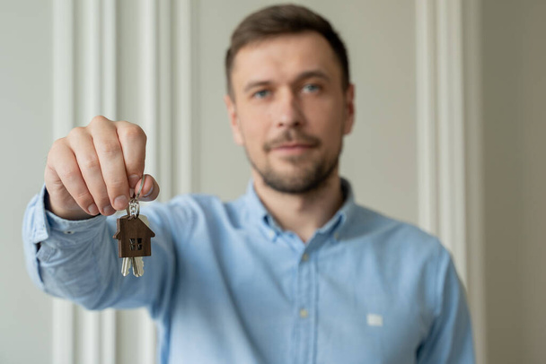 Man shows the keys to his new apartment in the living room.  - Zdjęcie, obraz