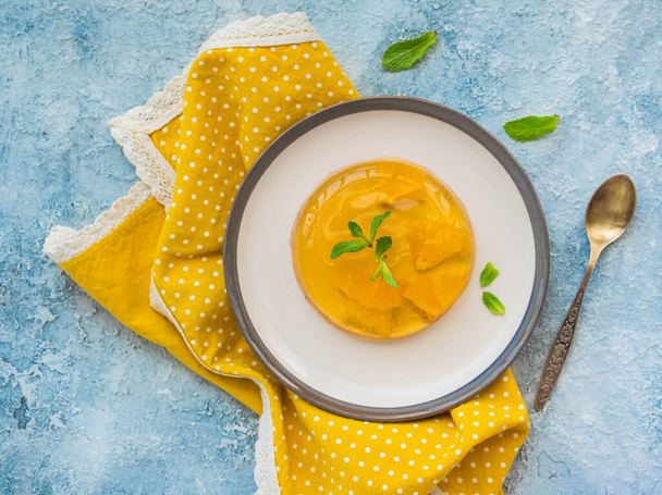 Dessert, orange jelly on a ceramic plate on a light concrete background. Desserts without baking - Zdjęcie, obraz