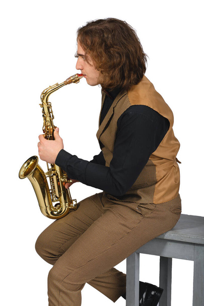 Jonge stijlvolle muzikant in vest en zwart shirt die saxofoon speelt. Geïsoleerd op witte achtergrond - Foto, afbeelding