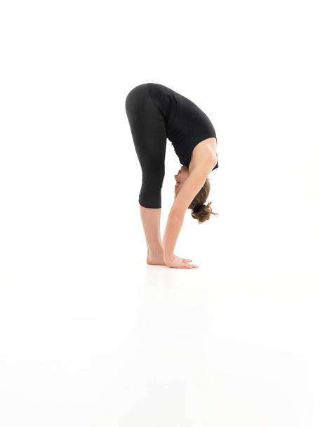 flexión hacia delante pose de yoga, mostrada por la joven hembra, soñada en bálsamo, sobre fondo blanco, vista lateral - Foto, imagen