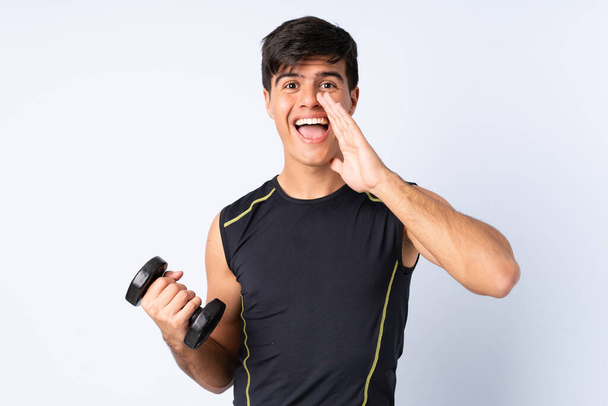 Sport man making weightlifting over isolated blue background shouting with mouth wide open - Photo, Image