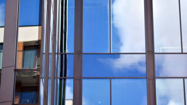 Moderní kancelářská budova detail, skleněný povrch na jasném pozadí oblohy. Průhledná skleněná stěna kancelářské budovy.   - Fotografie, Obrázek
