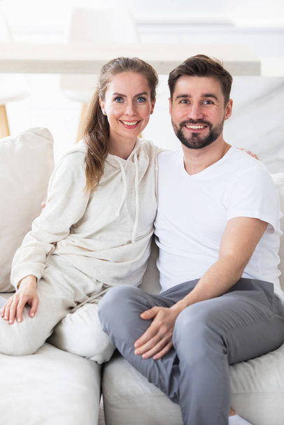 Portrait of mid adult couple relaxing in living room and smiling, looking at camera - Foto, Imagen
