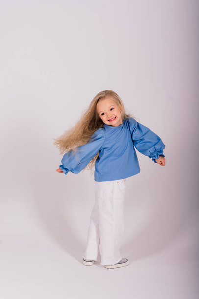 Portrait of a cheerful girl jumping and dancing against studio background - Foto, immagini
