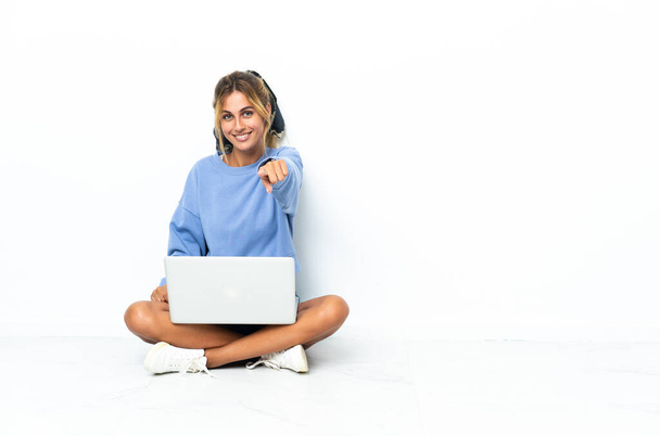 Young blonde Uruguayan girl with the laptop isolated on white background points finger at you with a confident expression - Фото, изображение