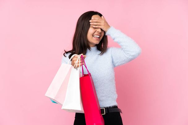 Mladá žena s nákupní taškou přes izolované růžové pozadí se hodně usmívá - Fotografie, Obrázek