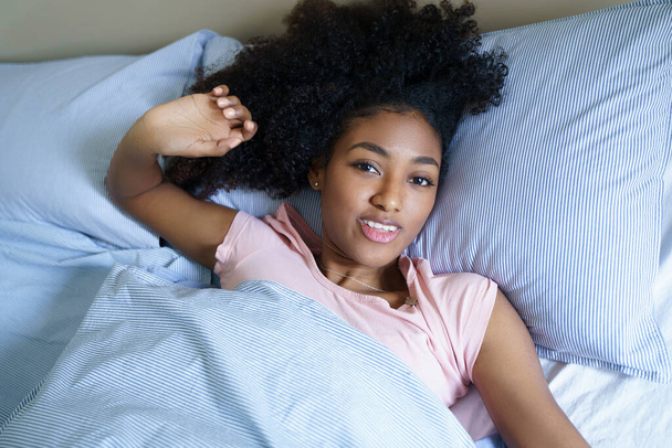 Afro-Amerikaanse vrouw stretching op bed in de ochtend - Foto, afbeelding