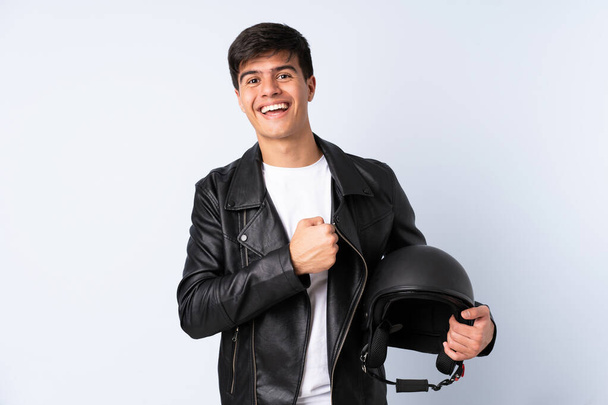 Man with a motorcycle helmet over isolated blue background celebrating a victory - Фото, изображение