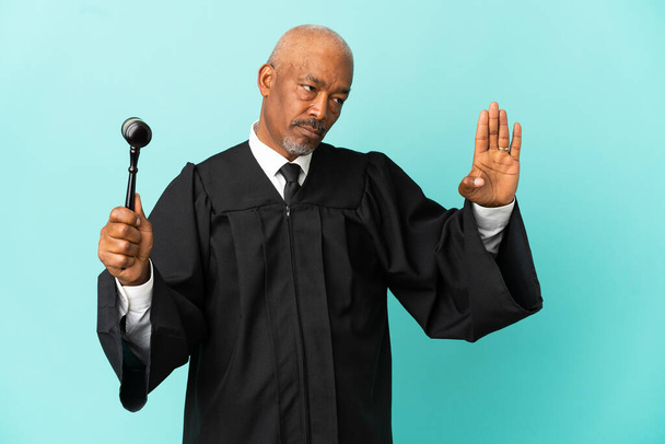 Richter Senior Mann isoliert auf blauem Hintergrund macht Stop-Geste und enttäuscht - Foto, Bild