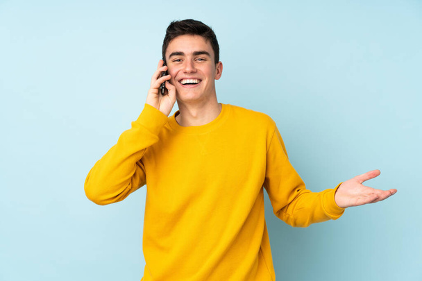 Підліток кавказький красивий чоловік ізольований на фіолетовому фоні, тримаючи розмову з мобільним телефоном з кимось
 - Фото, зображення