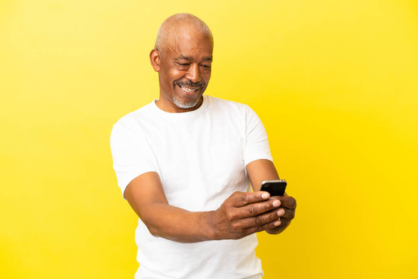 Cuban Senior isolated on yellow background making a selfie - Photo, Image