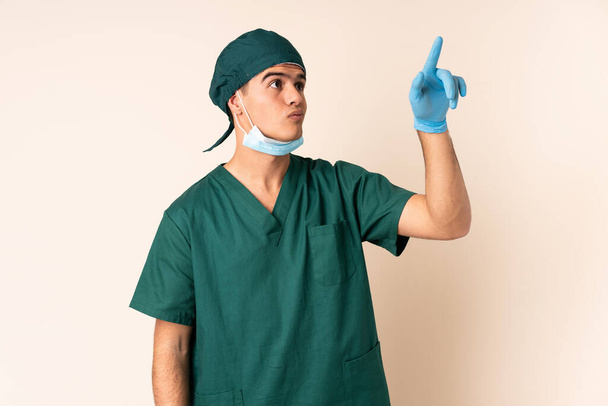 Surgeon man in blue uniform over isolated background touching on transparent screen - Foto, afbeelding